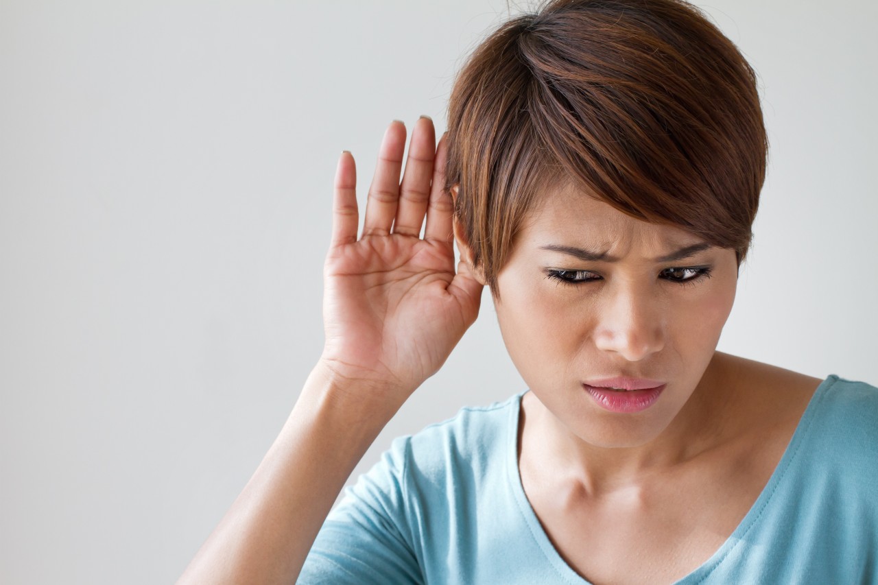 close up image of woman holding her ear representing hearing loss