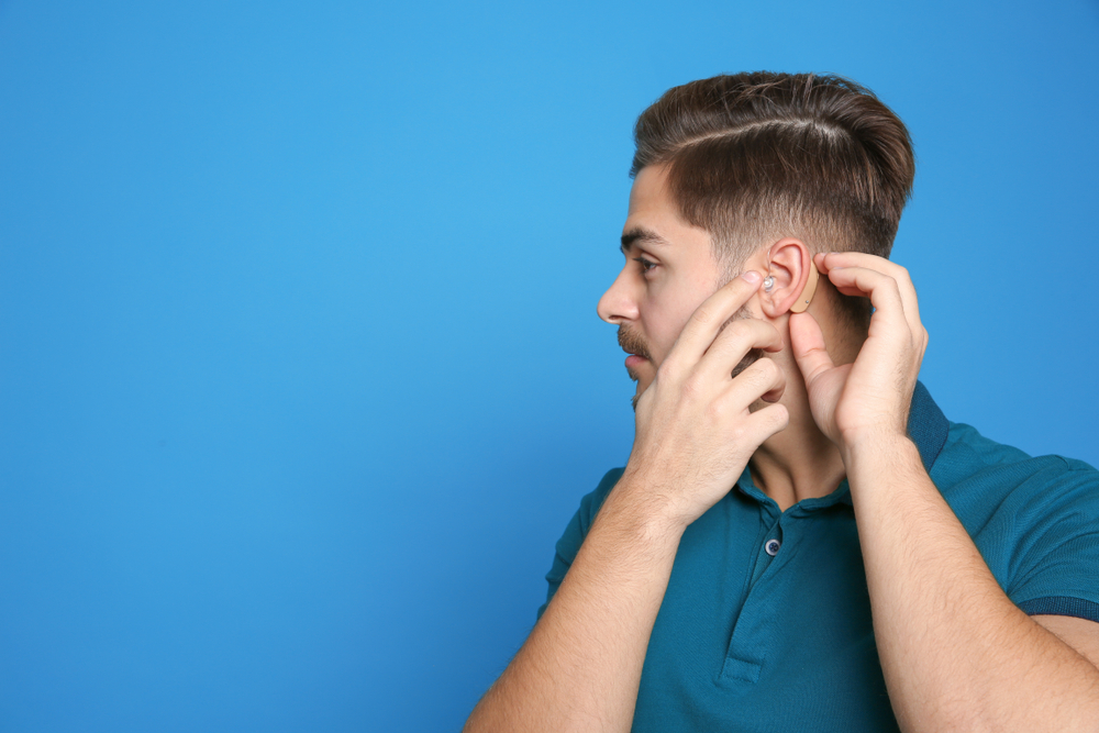 A young man wears his hearing aid covered by his insurance and provided by Memorial Hearing